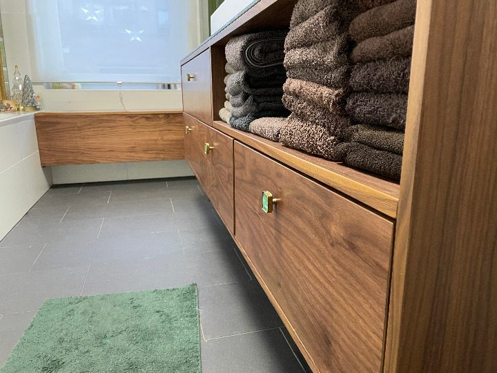 Badschrank in Nussbaum mit offenen Fächern für gestapelte Handtücher.