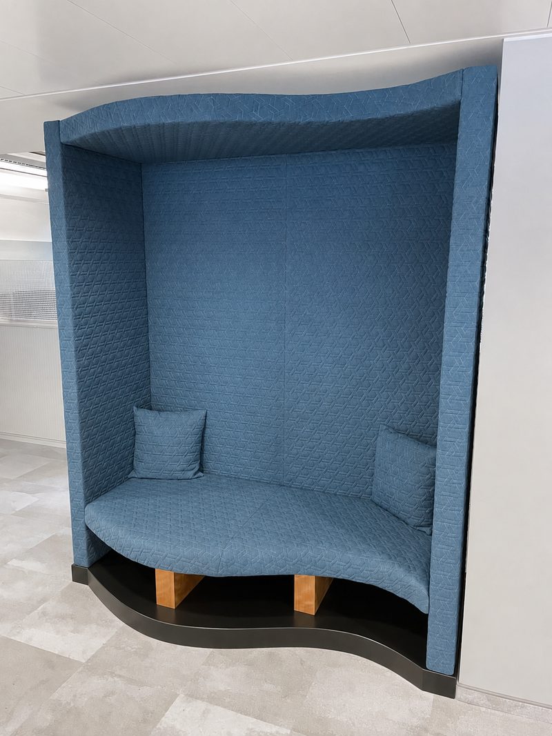 Gepolsterte Sitzlounge mit hoher Rückwand und Haube, blauer Bezug.